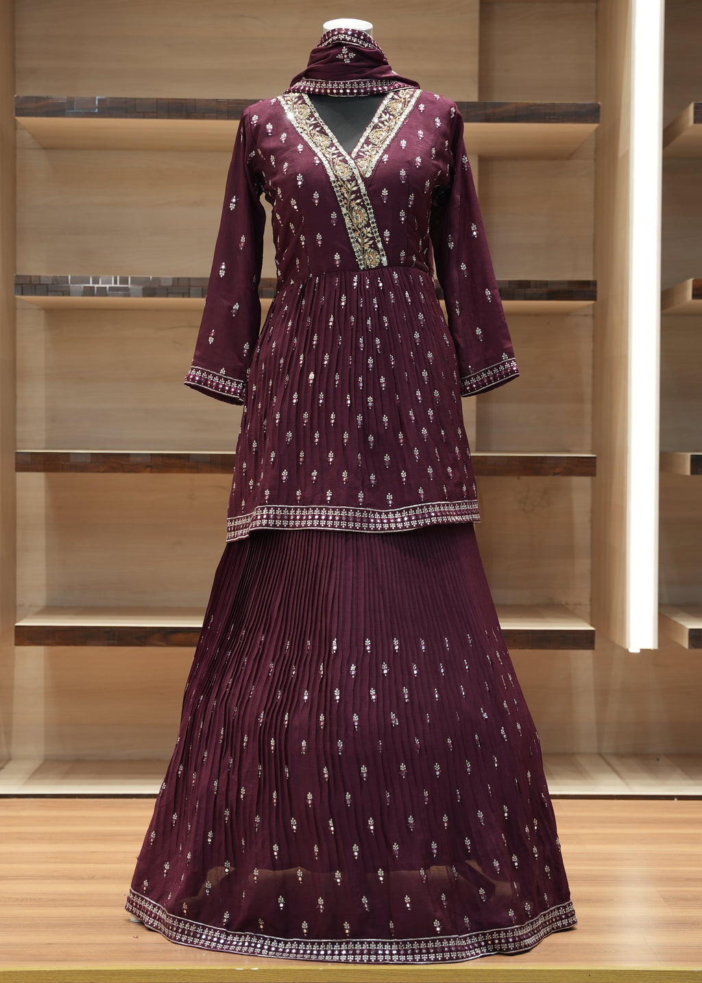 Maroon traditional outfit with intricate patterns on a wooden shelf.