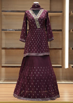 Maroon traditional outfit with intricate patterns on a wooden shelf.