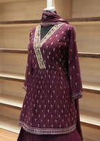 Purple traditional outfit with intricate patterns on a wooden stand.