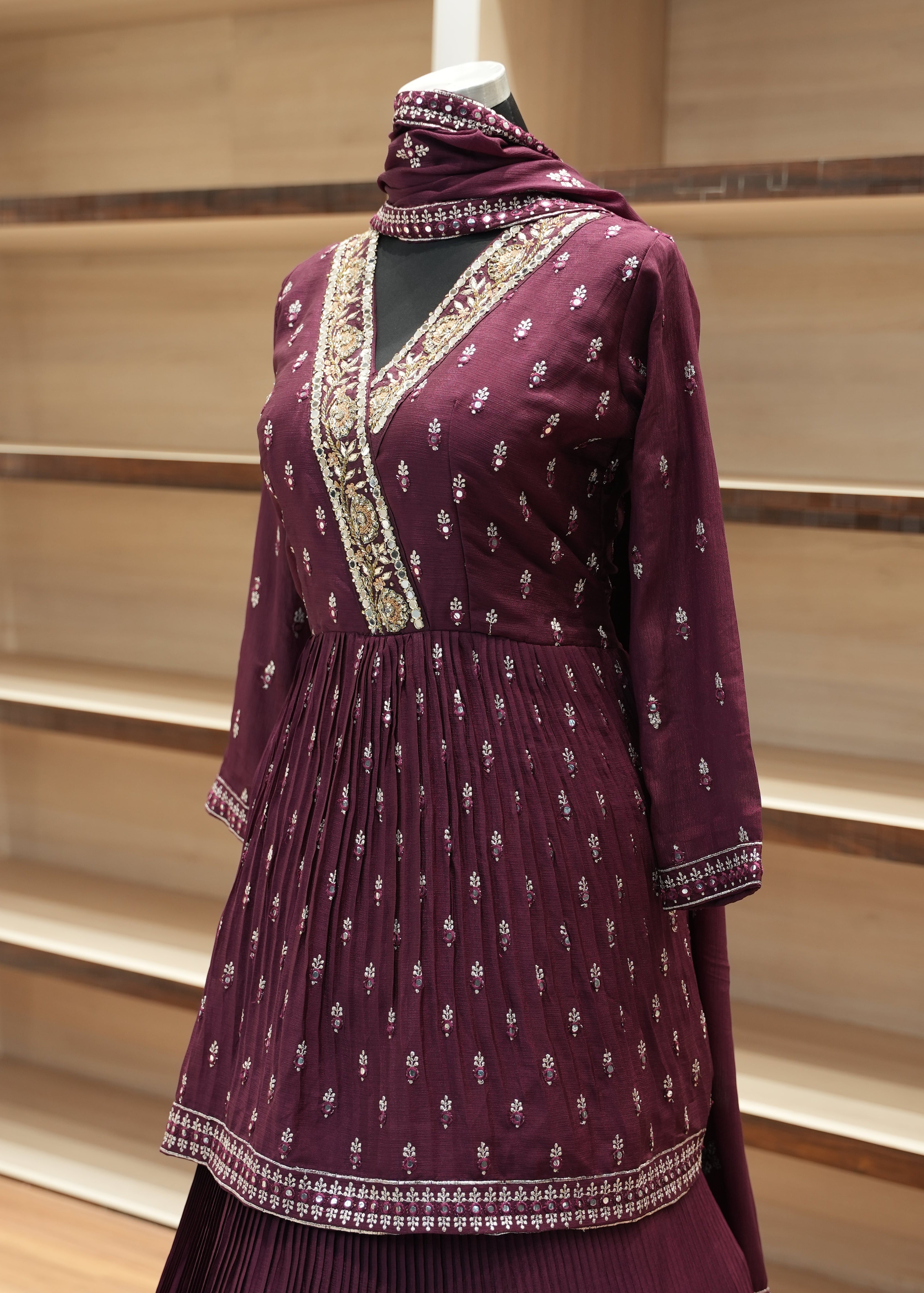 Purple traditional outfit with intricate patterns on a wooden stand.