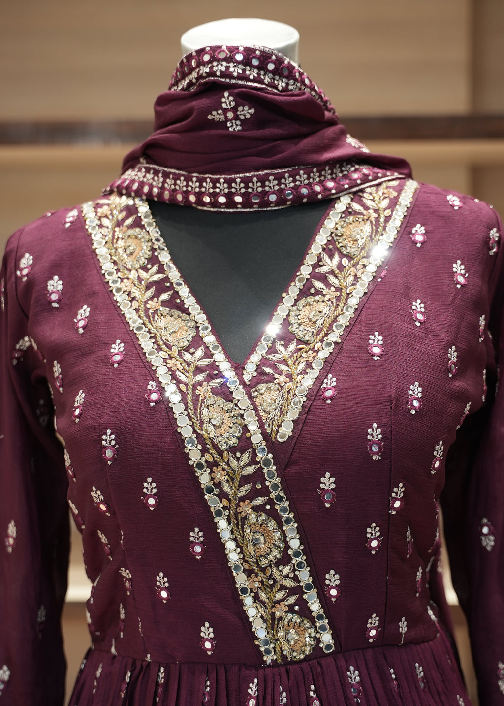 Purple fabric with gold embroidery on a mannequin against a neutral background