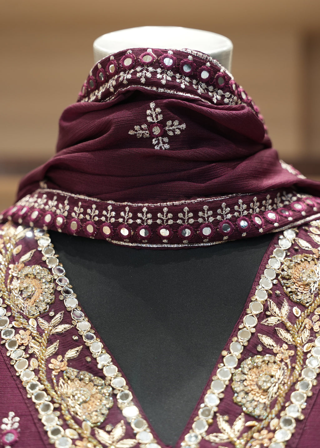 Purple embroidered garment with a matching headscarf on a mannequin against a blurred background