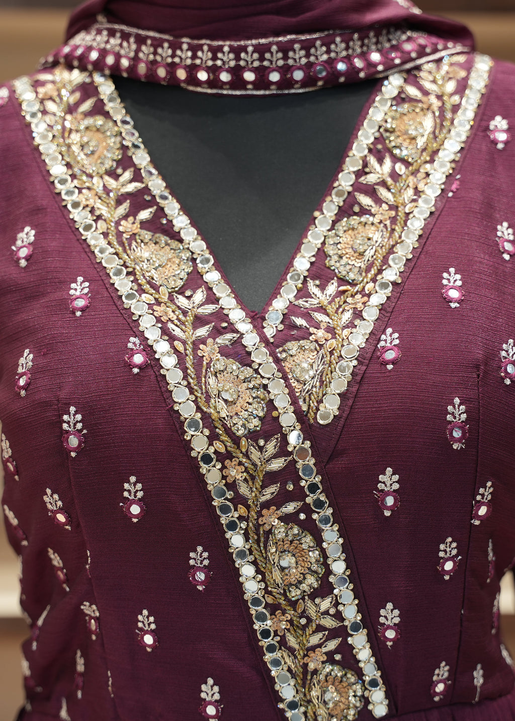 Maroon embroidered garment with a matching headscarf on a blurred background