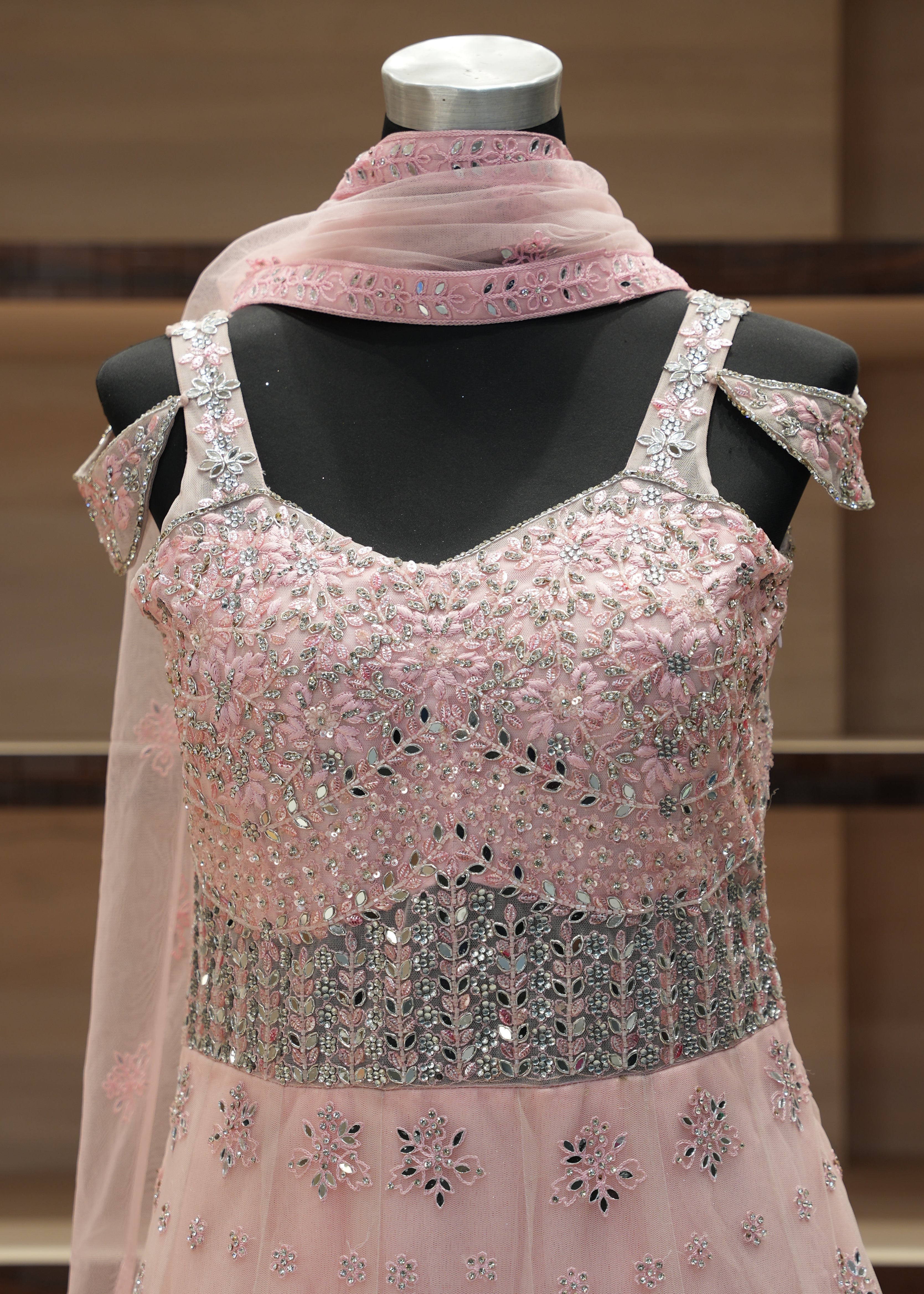 Pink embroidered dress on a mannequin against a neutral background