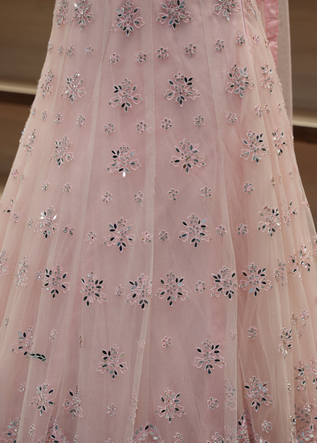 Close-up of pink fabric with floral embroidery on a neutral background