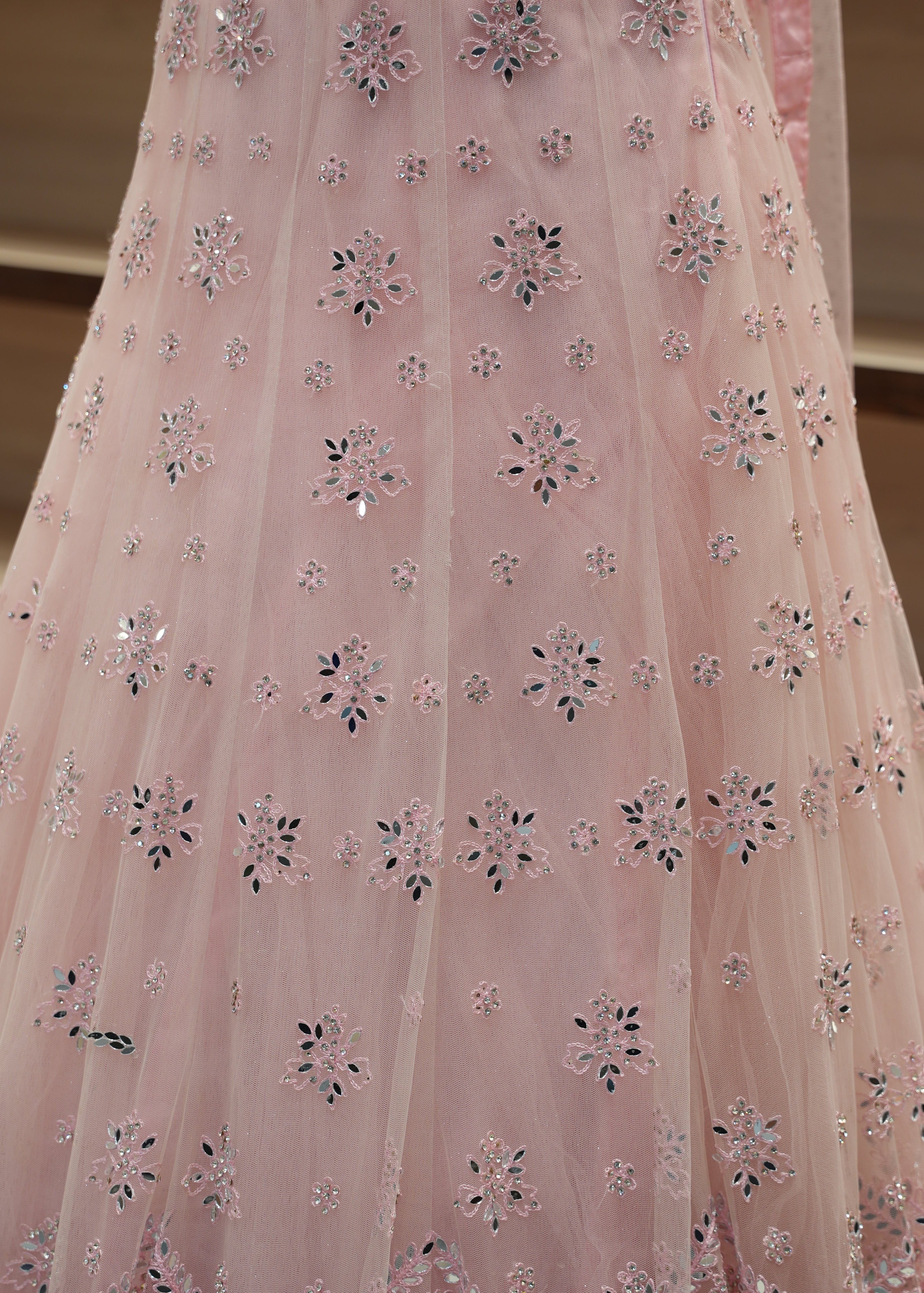 Close-up of pink fabric with floral embroidery on a neutral background