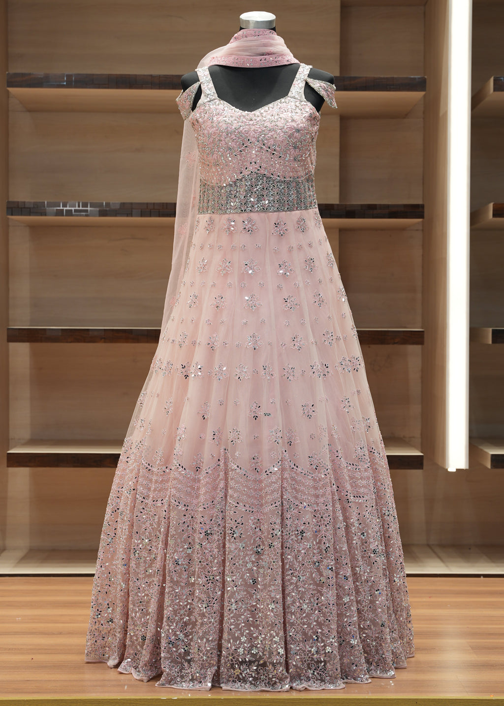 Pink evening gown with sequin details on a mannequin against a wooden background