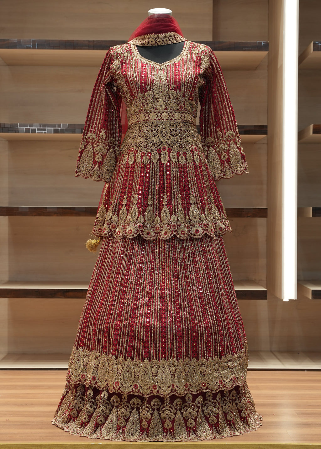 Decorative red and gold garment on a mannequin against a wooden background