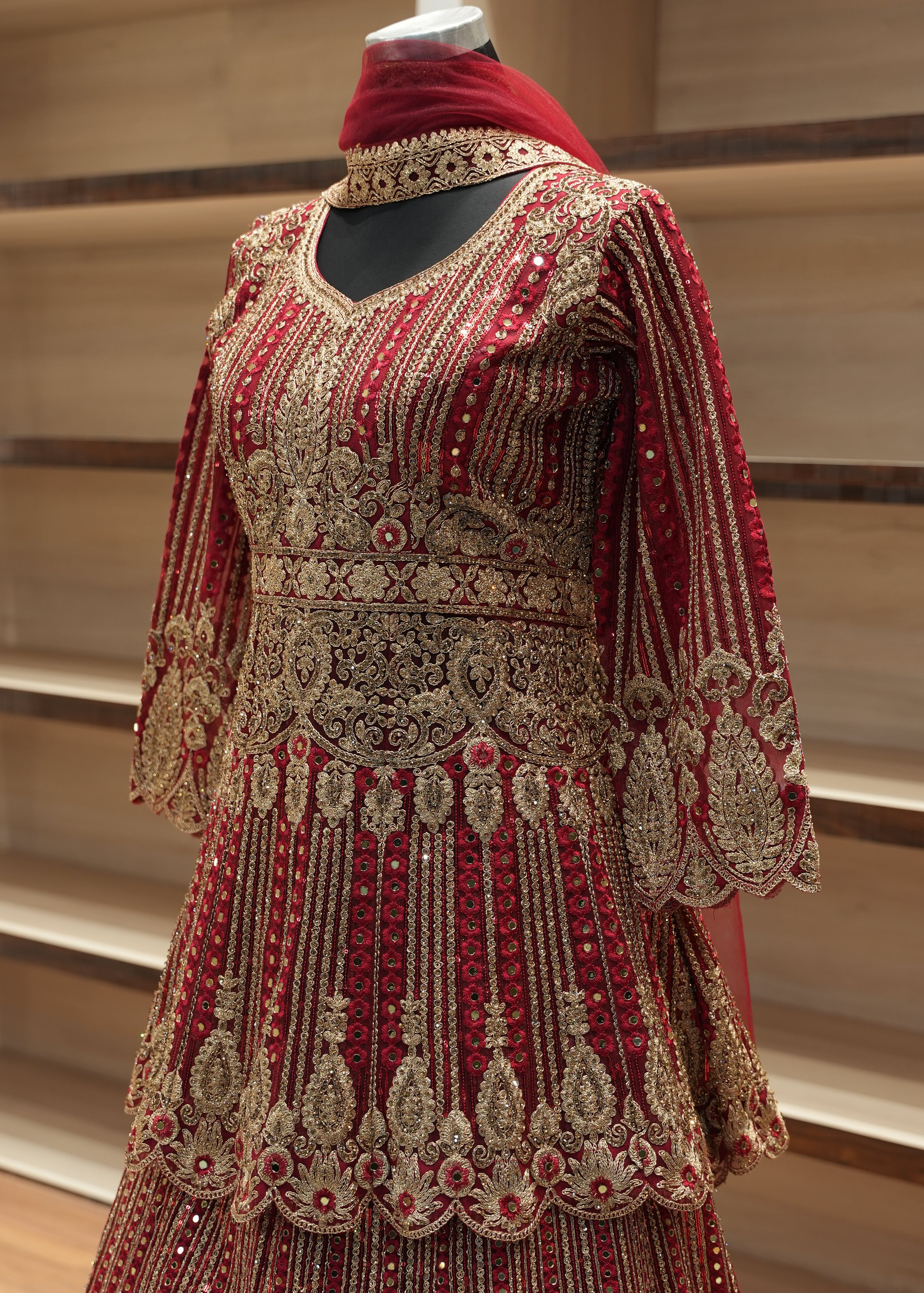 Red and gold embroidered garment on a mannequin against a neutral background