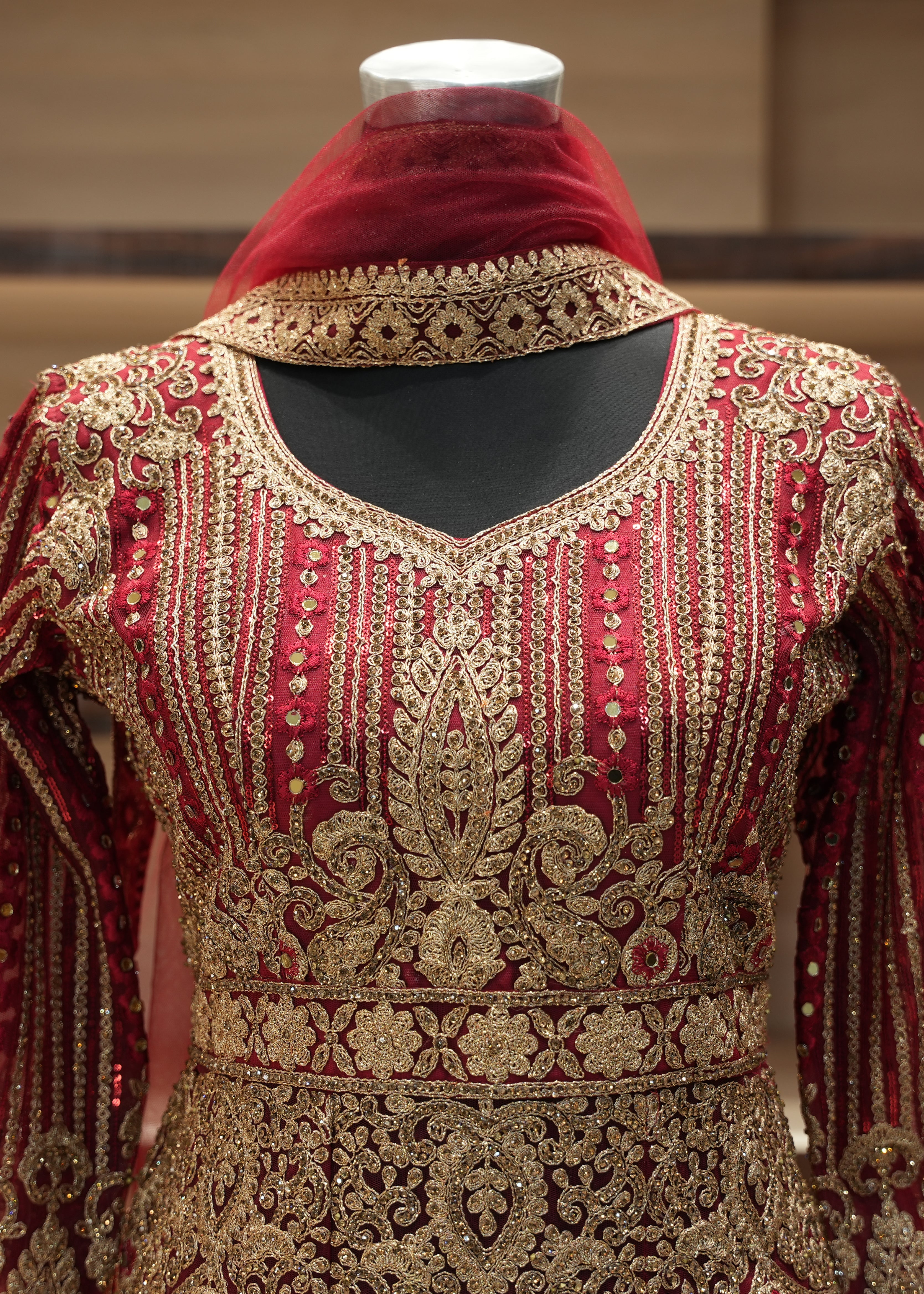 Decorative red and gold garment with intricate patterns on a mannequin.