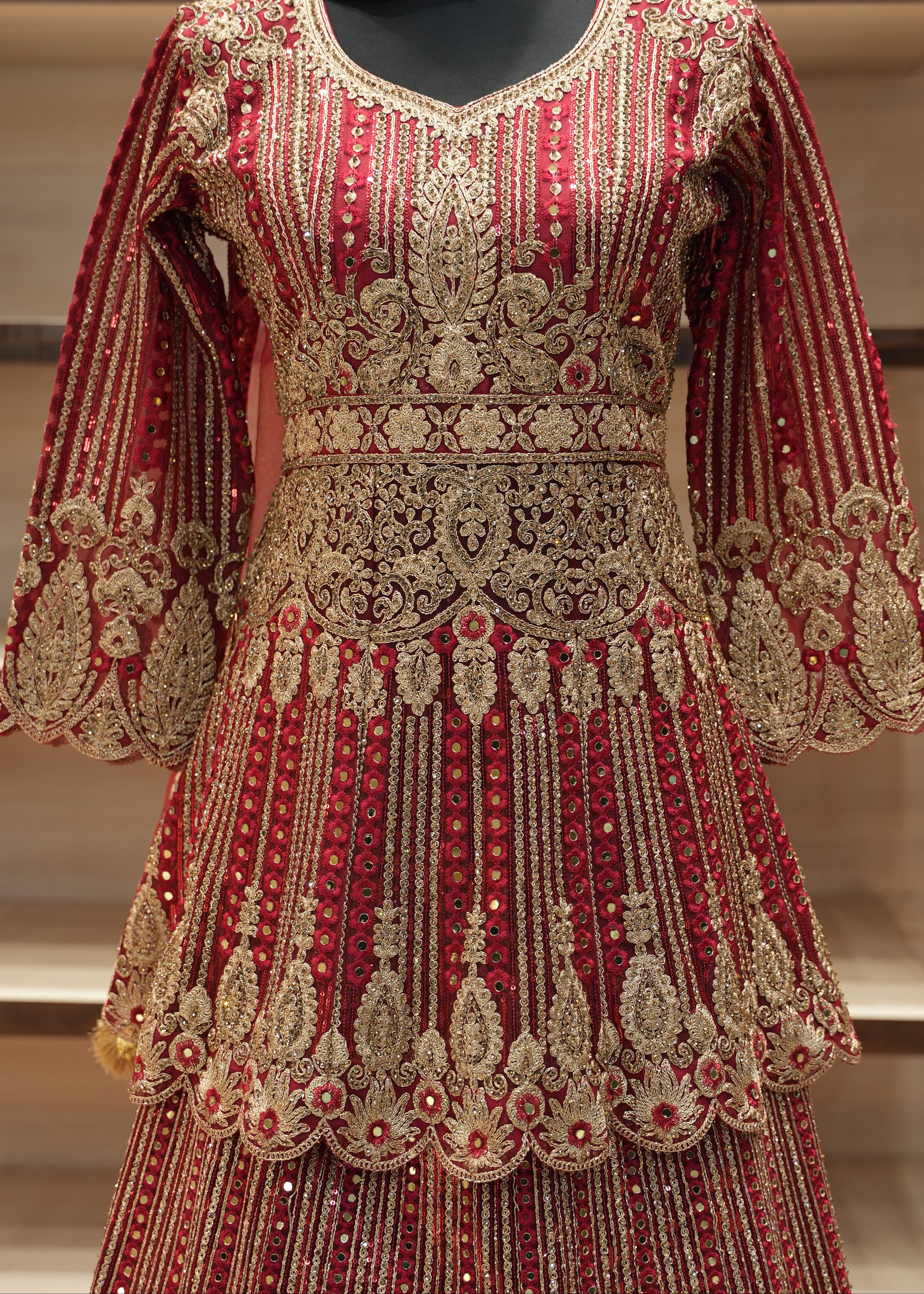 Decorative red and gold dress with intricate patterns on a wooden shelf.