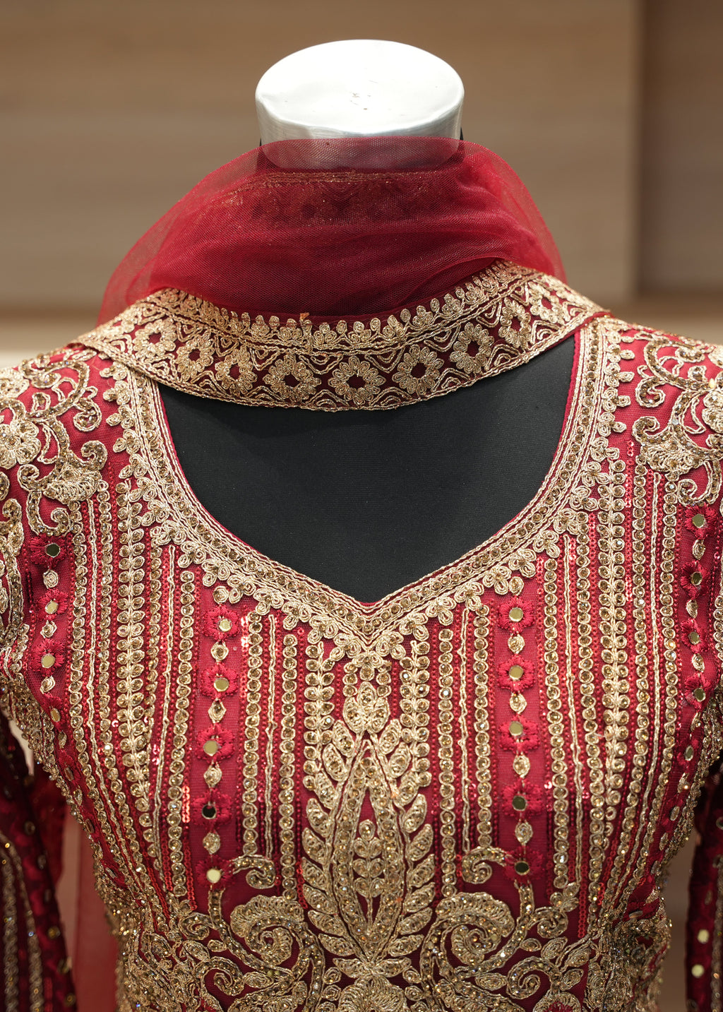 Red and gold embroidered traditional outfit on a mannequin with a blurred background