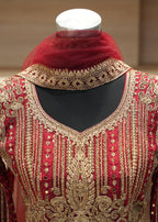 Red and gold embroidered traditional outfit on a mannequin with a blurred background