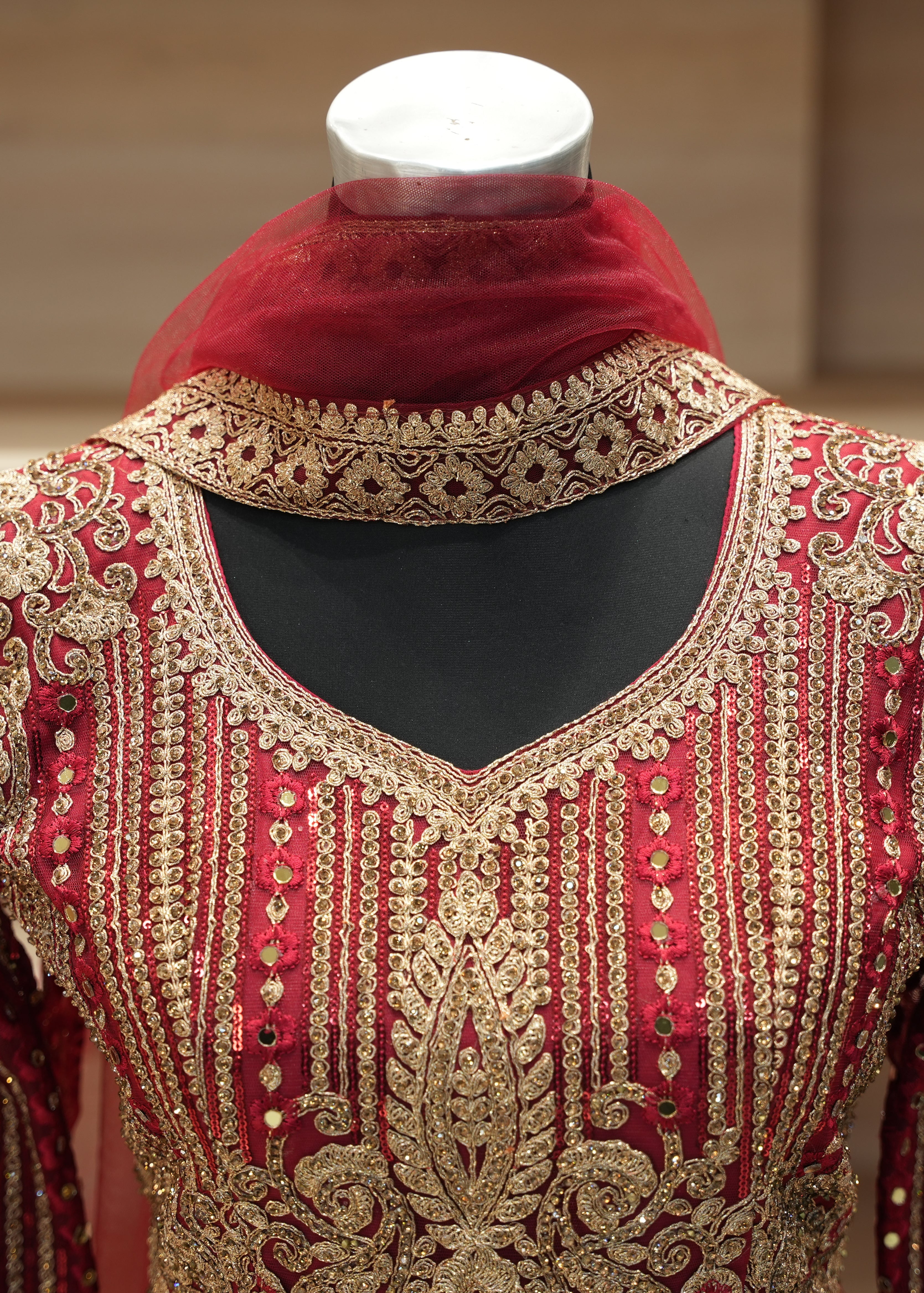 Red and gold embroidered traditional outfit on a mannequin with a blurred background