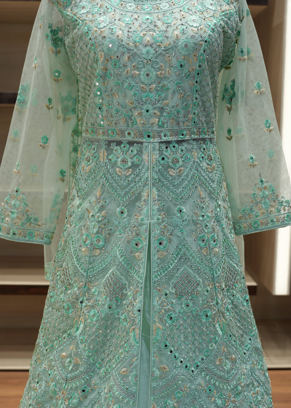 Teal embroidered fabric with intricate patterns on a wooden surface