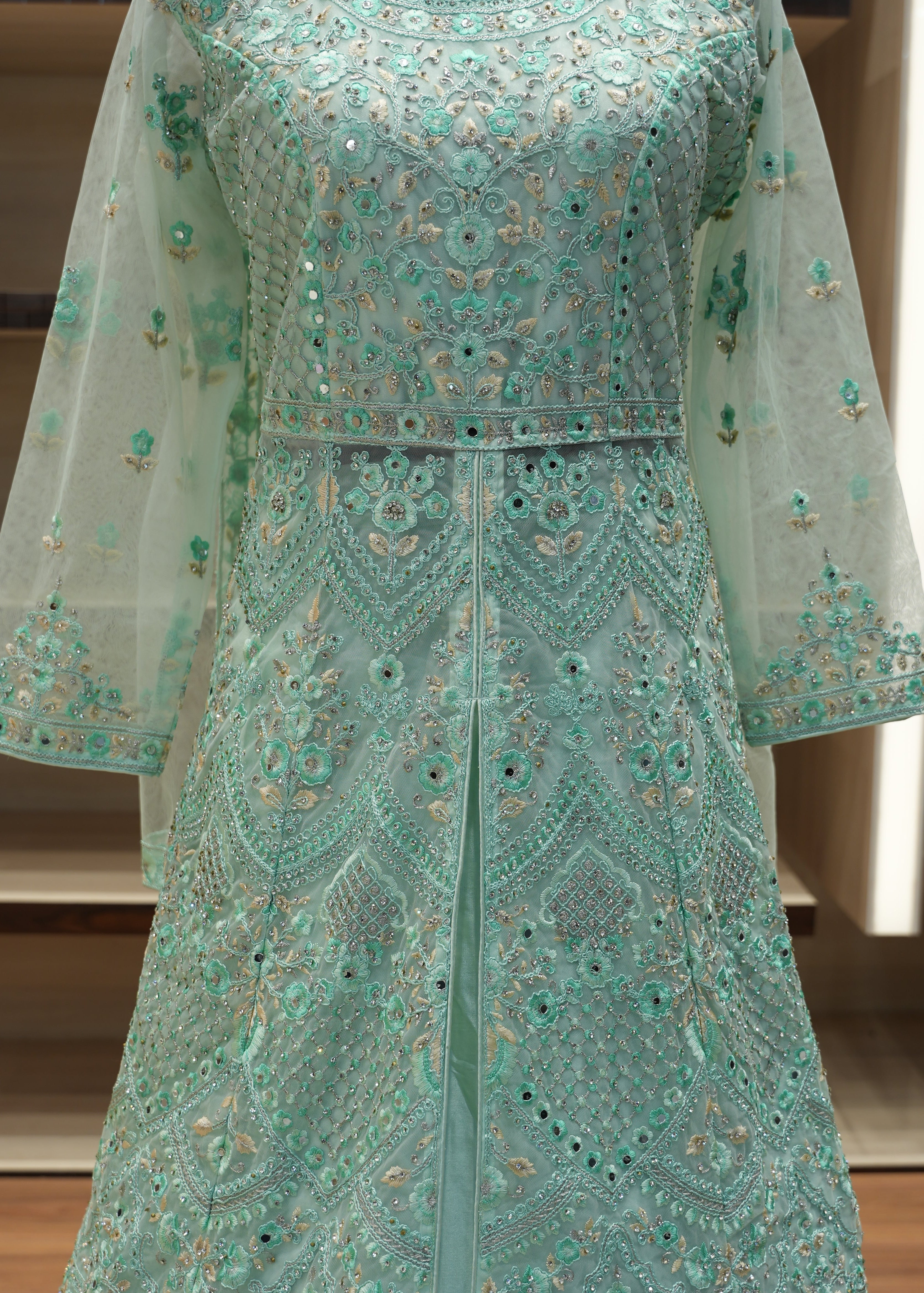 Teal embroidered fabric with intricate patterns on a wooden surface