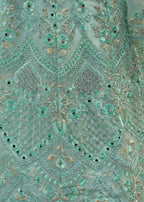 Close-up of a teal embroidered fabric with intricate patterns