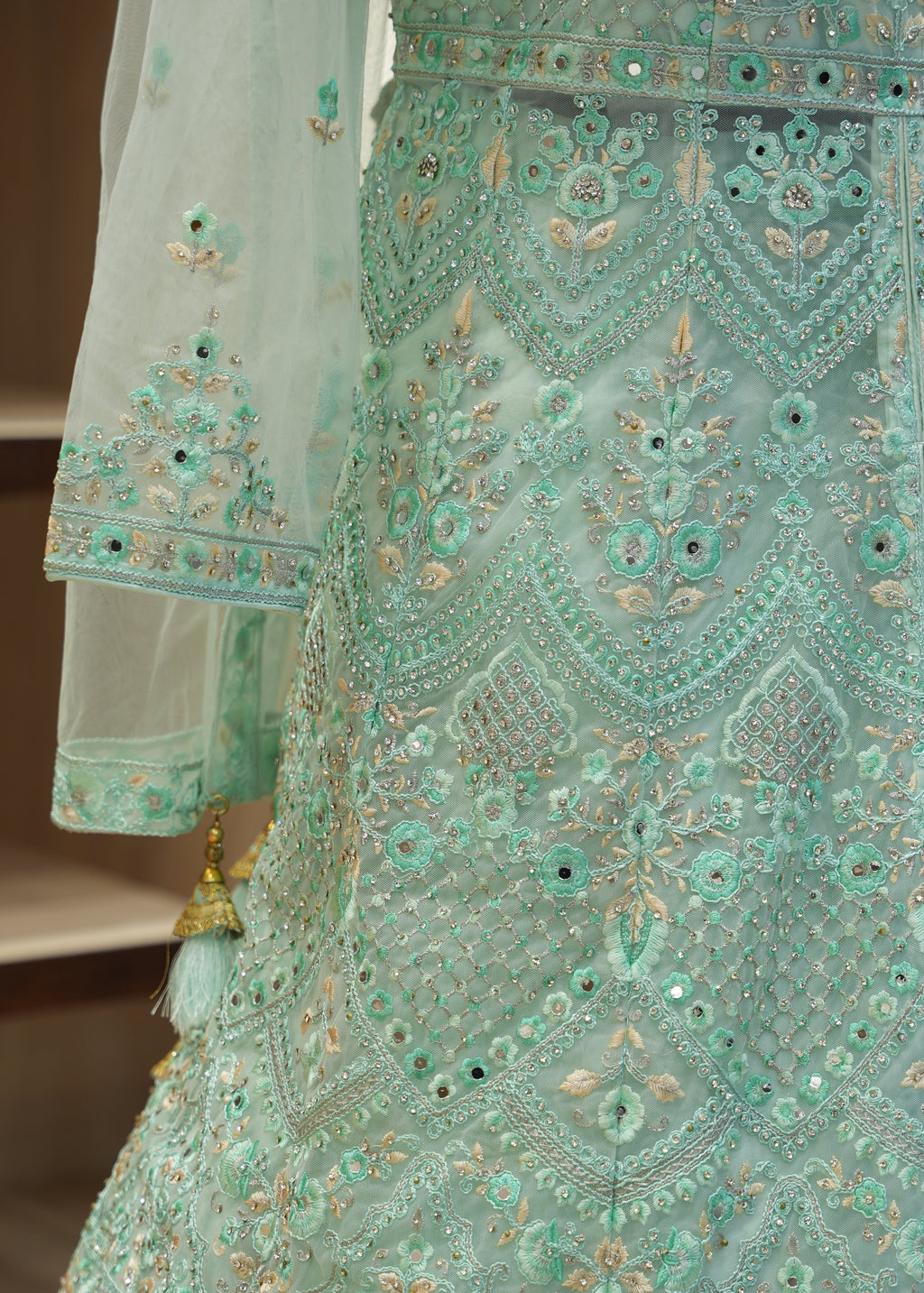 Mint green embroidered traditional outfit with intricate patterns on a blurred background