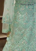Mint green embroidered traditional outfit with intricate patterns on a blurred background