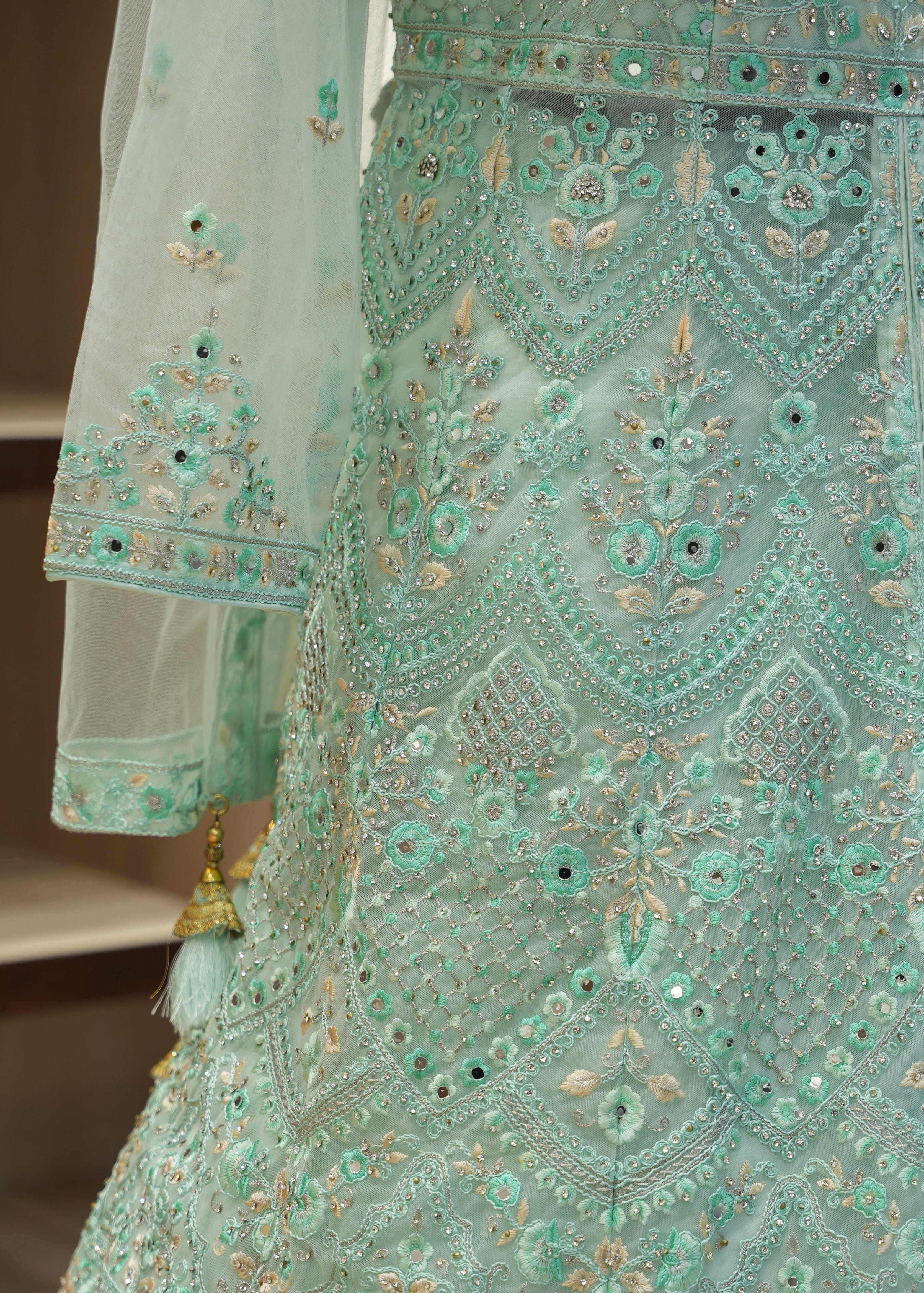 Mint green embroidered traditional outfit with intricate patterns on a blurred background