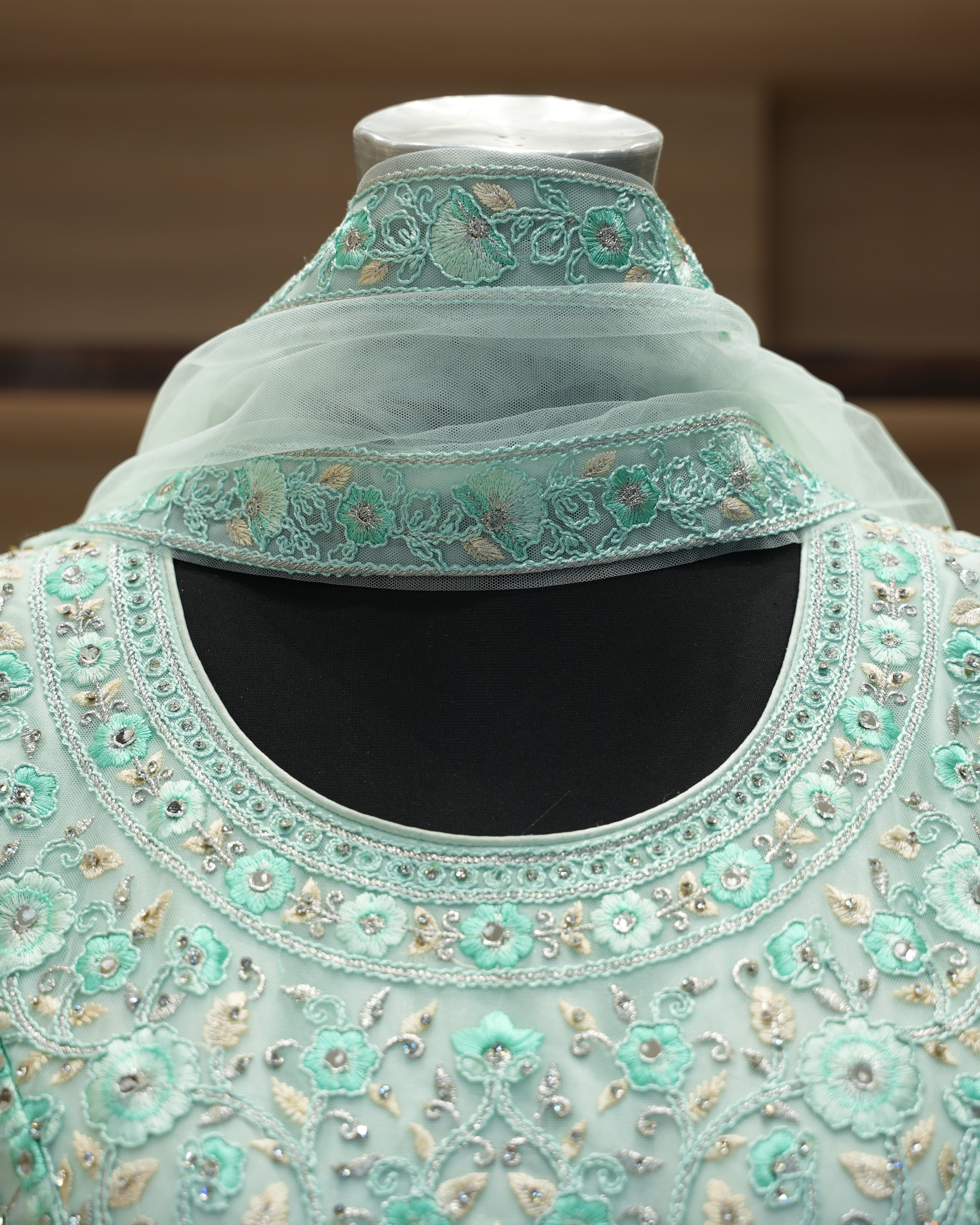 Light blue embroidered garment on a mannequin with a blurred background