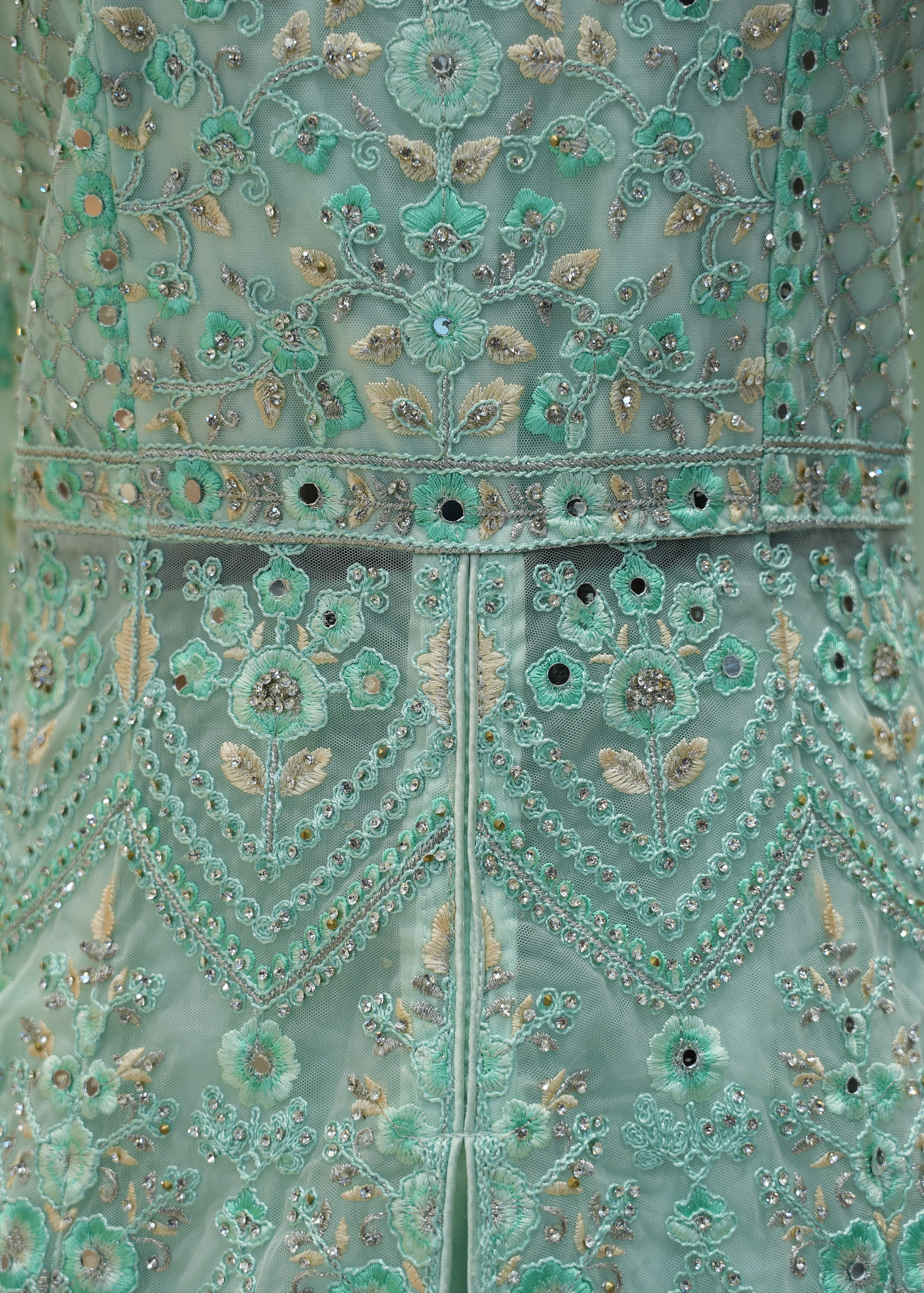 Close-up of a teal embroidered garment with intricate patterns
