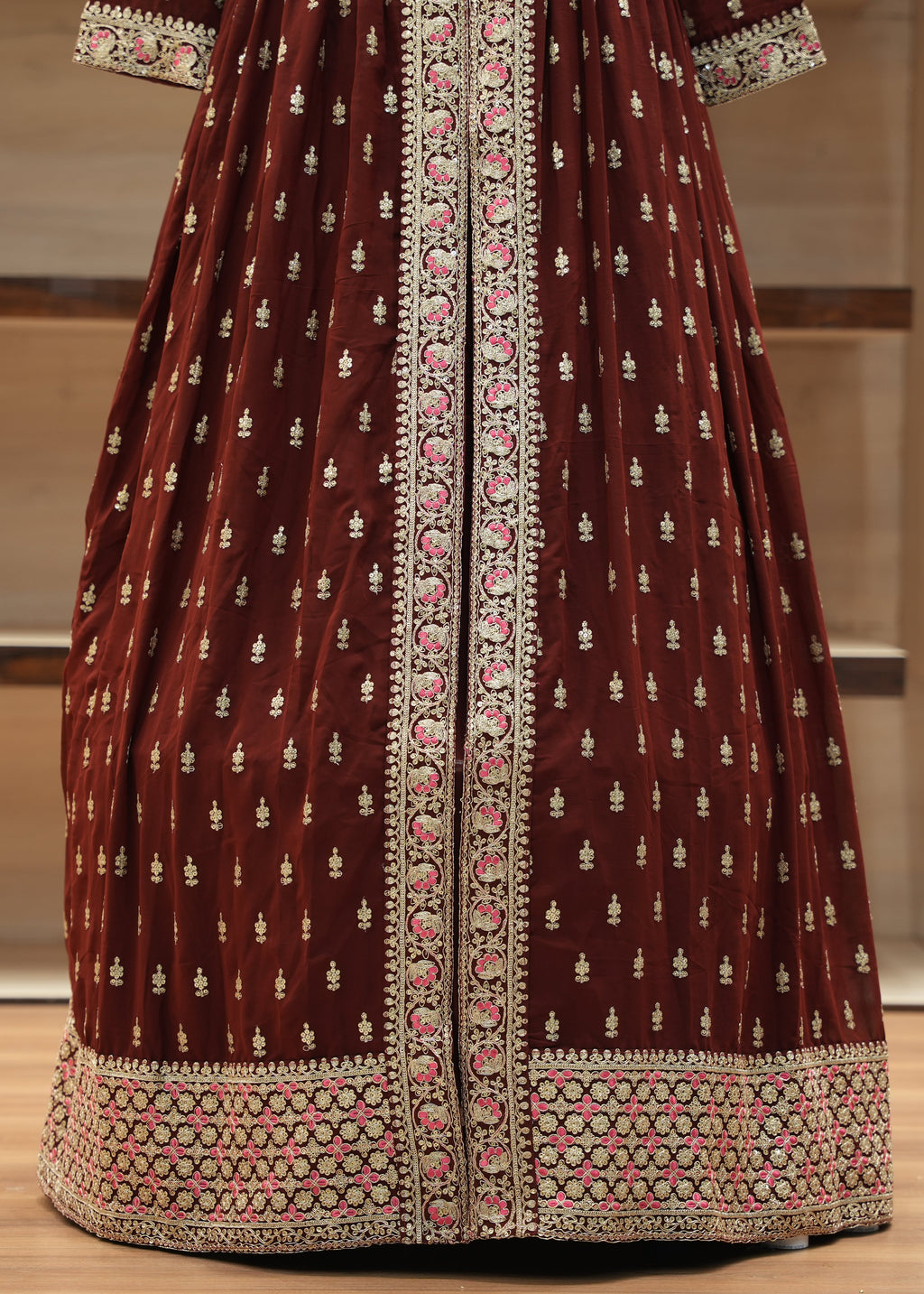Maroon traditional outfit with intricate white and pink patterns on a neutral background