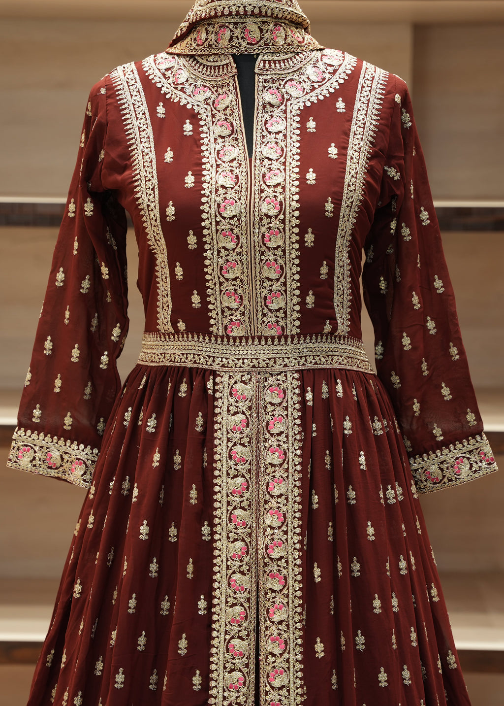 Maroon embroidered traditional dress on a mannequin against a neutral background