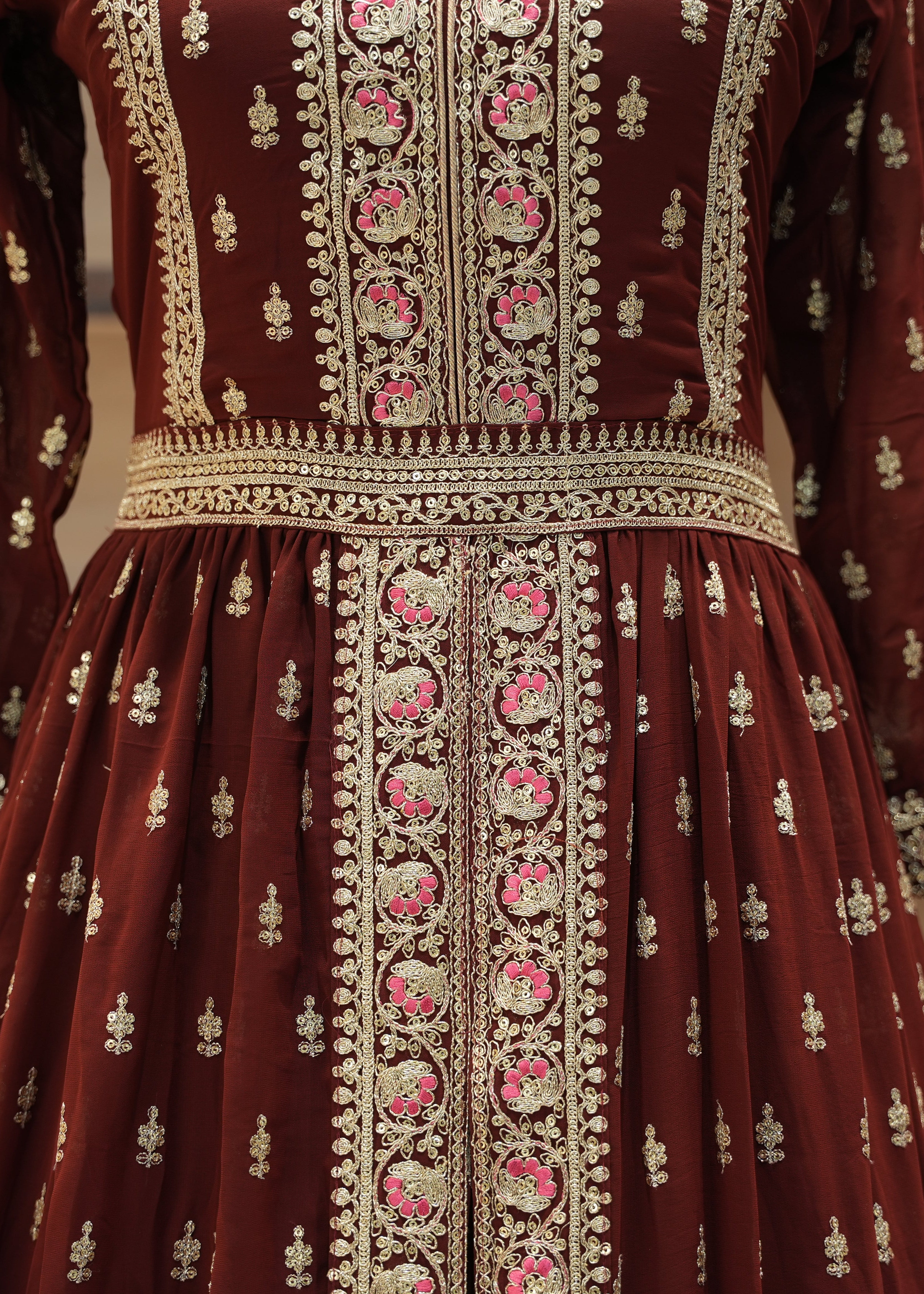 Maroon traditional outfit with intricate white and pink embroidery on a neutral background