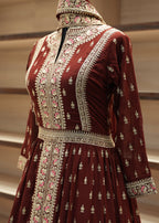 Maroon fabric with intricate white and pink embroidery on a metallic rod.
