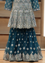 Blue and white embroidered traditional outfit on a wooden stand.