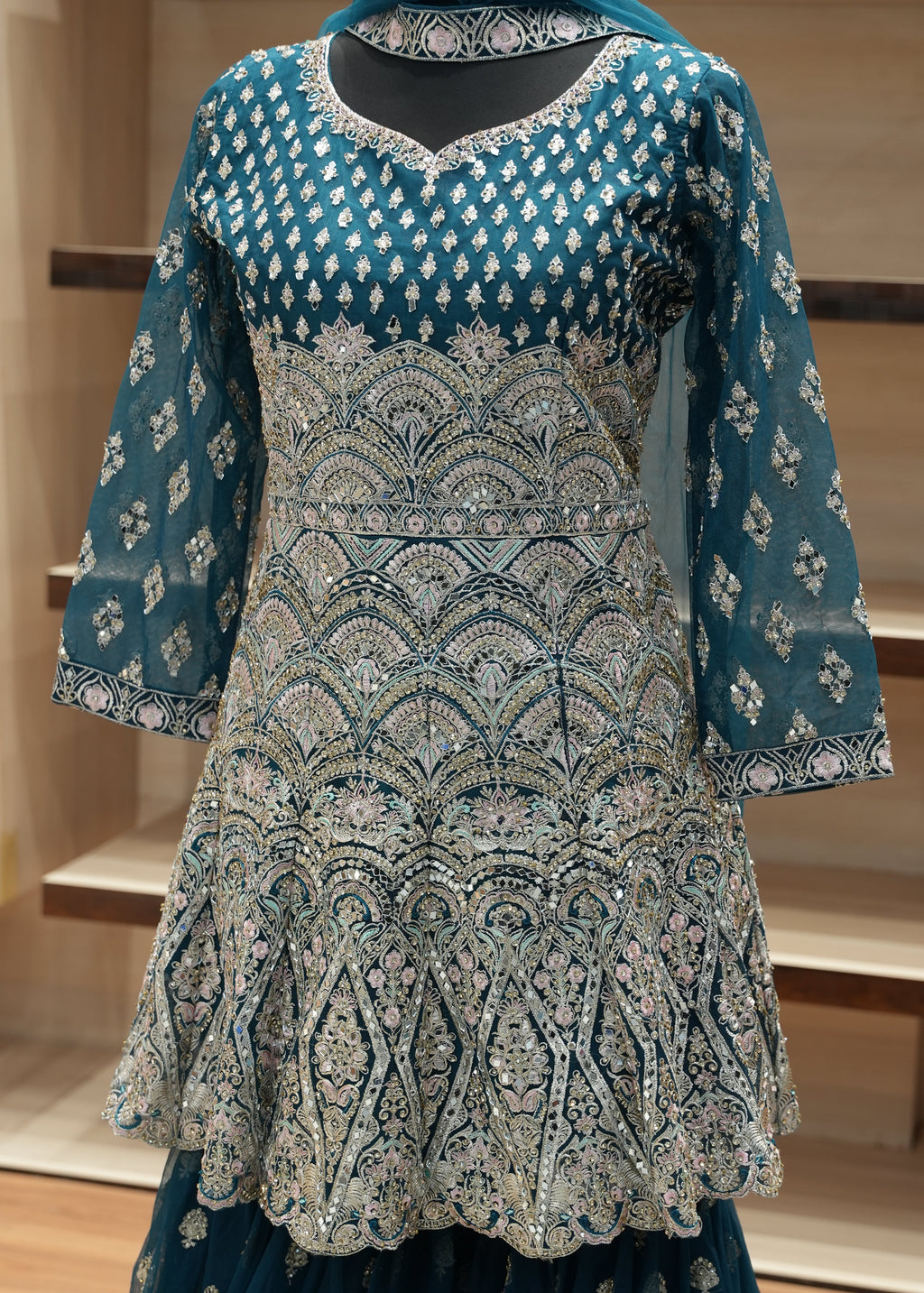 Blue embroidered garment on a mannequin with a blurred background