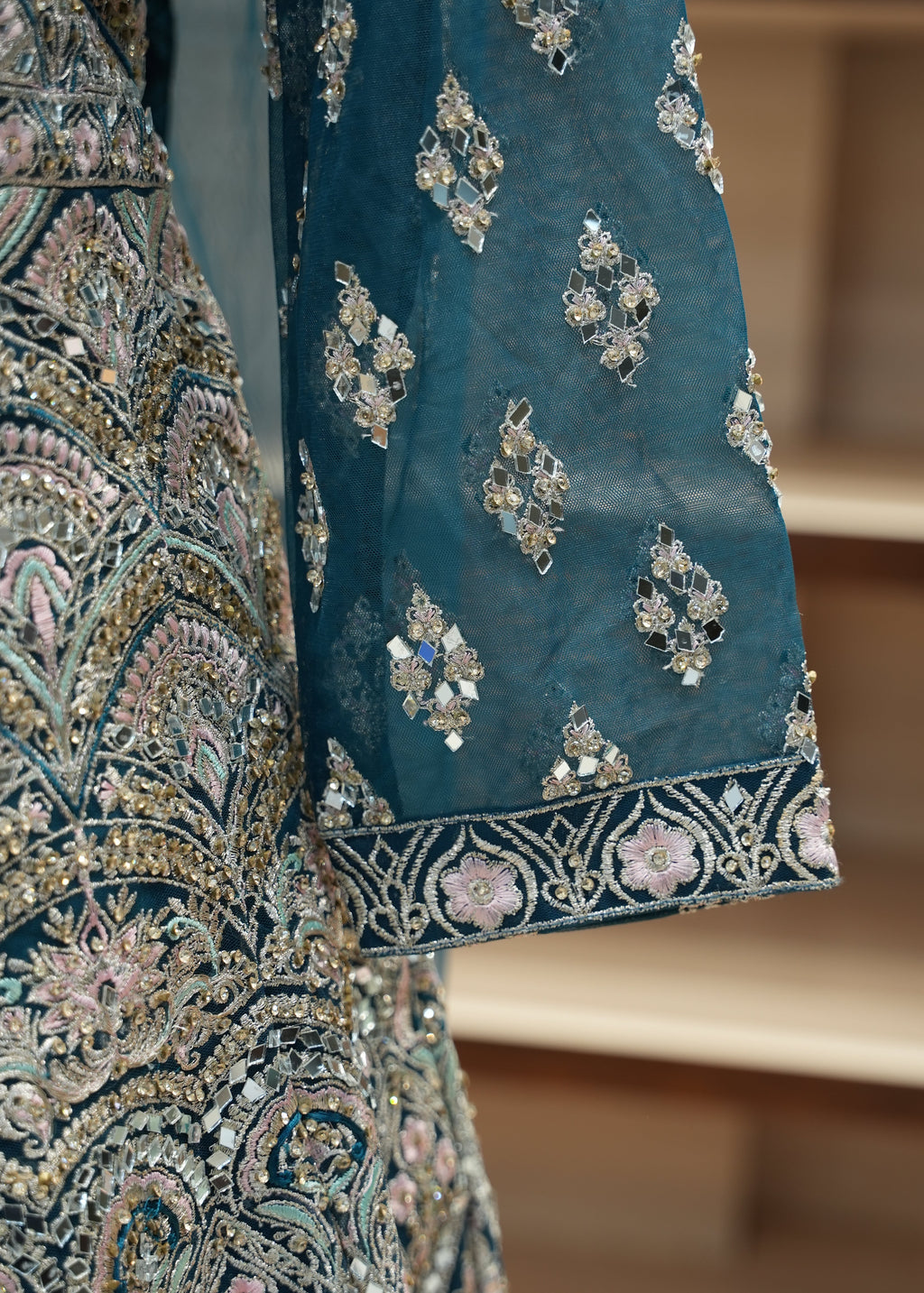 Close-up of a blue fabric with intricate gold and silver embroidery on a blurred background