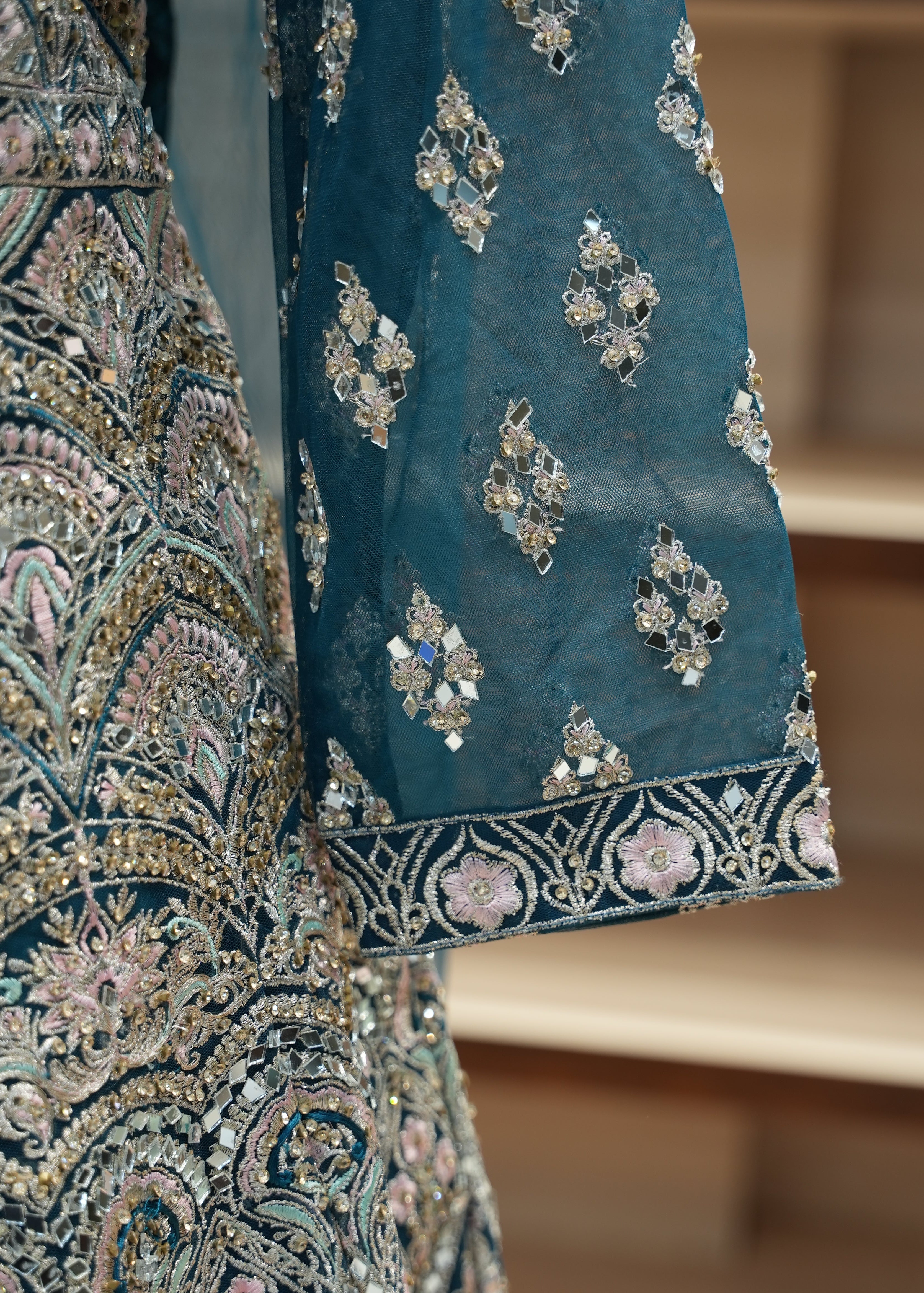 Close-up of a blue fabric with intricate gold and silver embroidery on a blurred background