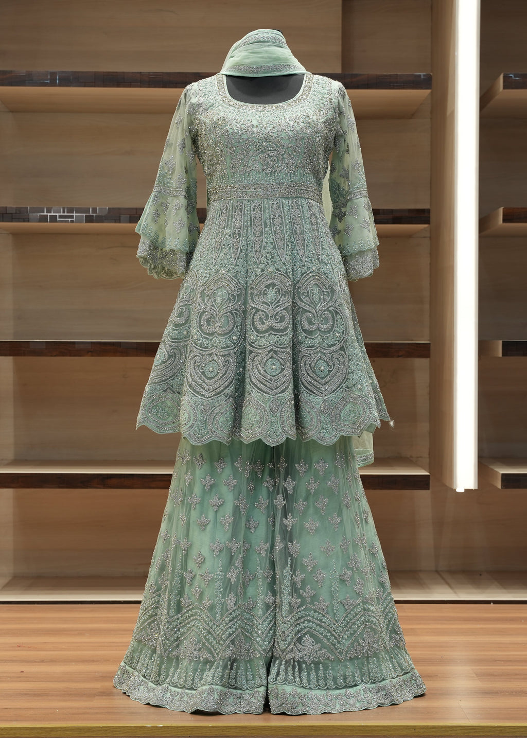 Green embroidered outfit on a wooden shelf