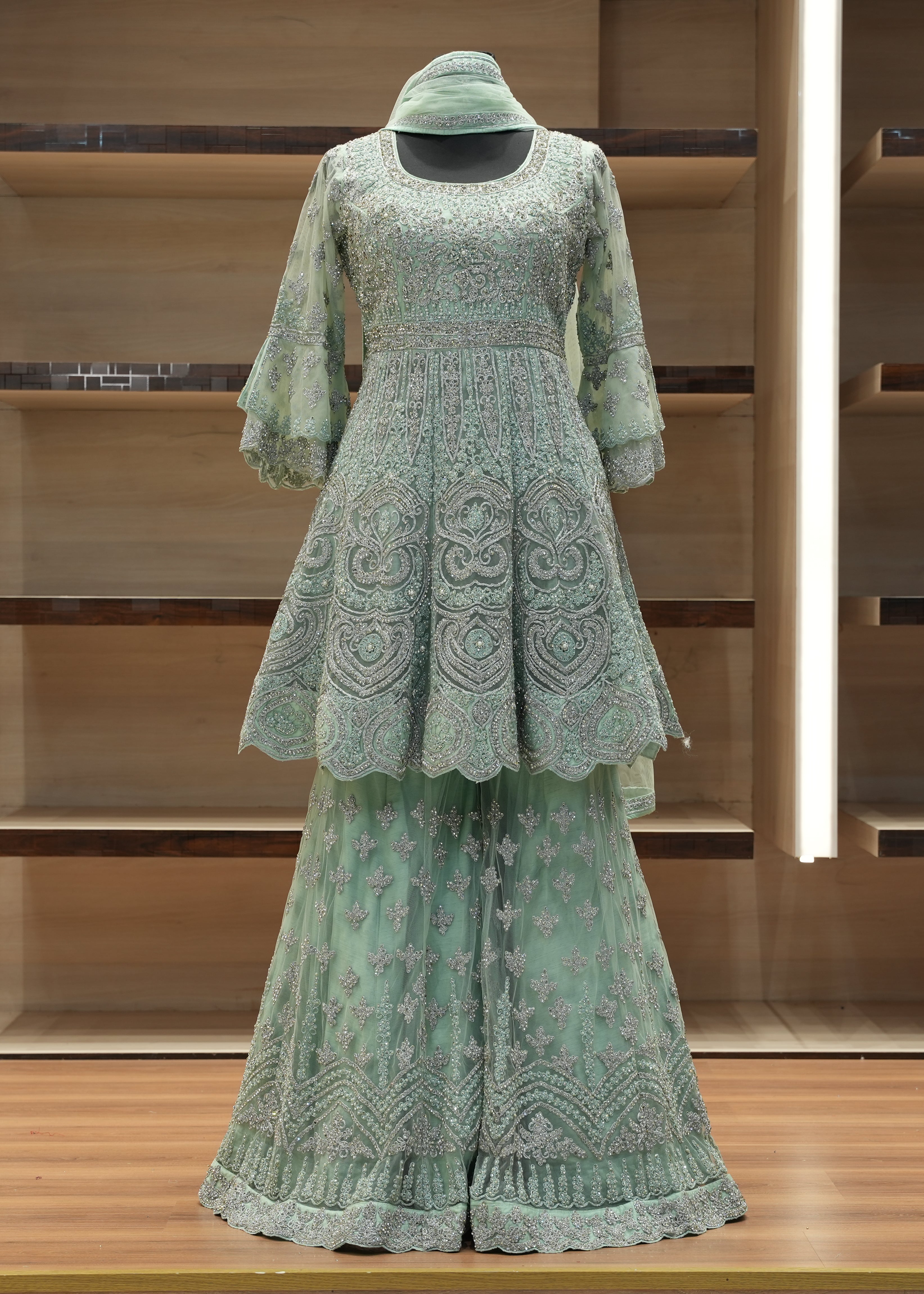 Green embroidered outfit on a wooden shelf