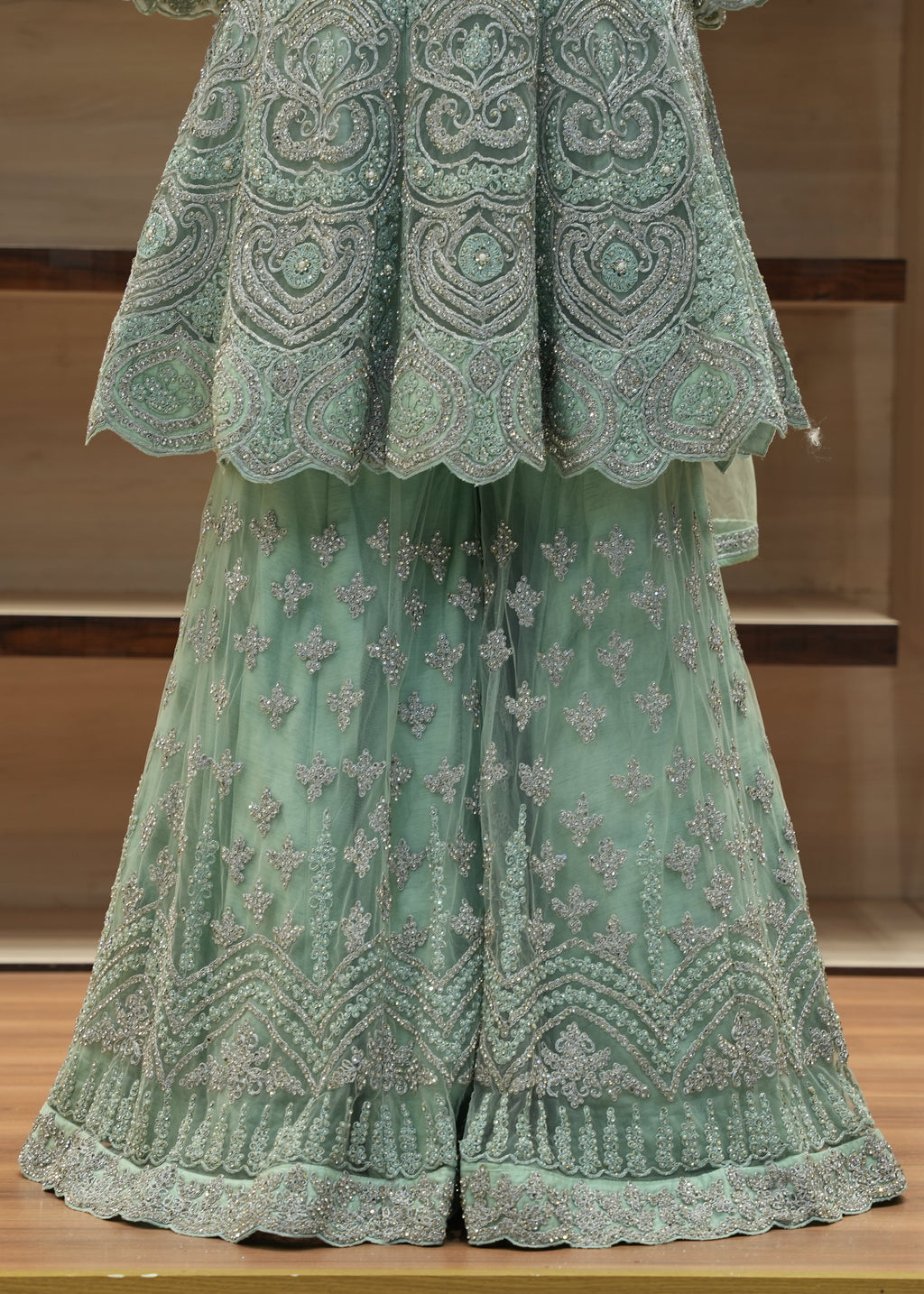 Green embroidered outfit on a wooden surface with a neutral background