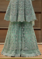 Green embroidered outfit on a wooden surface with a neutral background