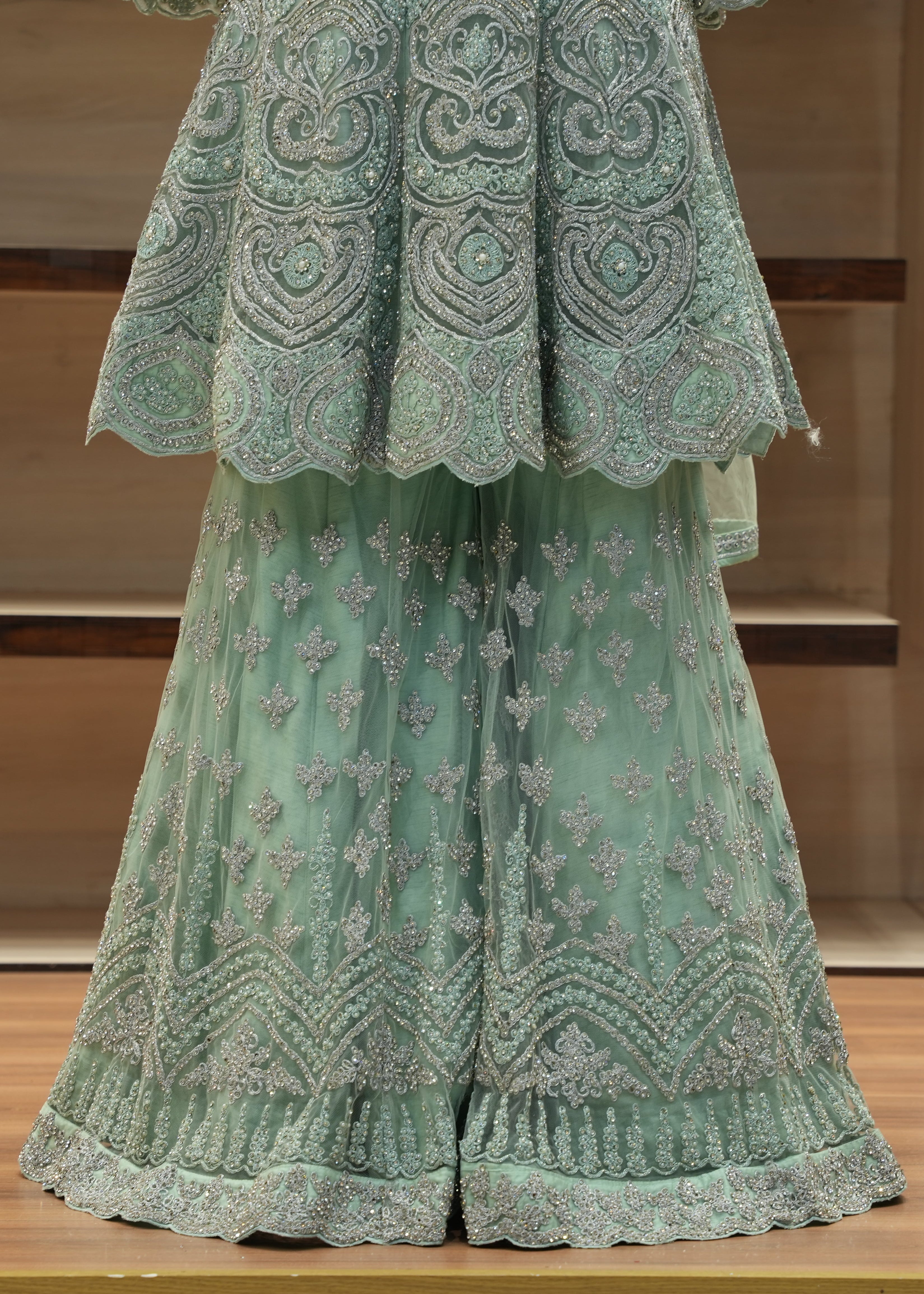 Green embroidered outfit on a wooden surface with a neutral background