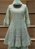 Green embroidered dress with matching headscarf on a wooden shelf background