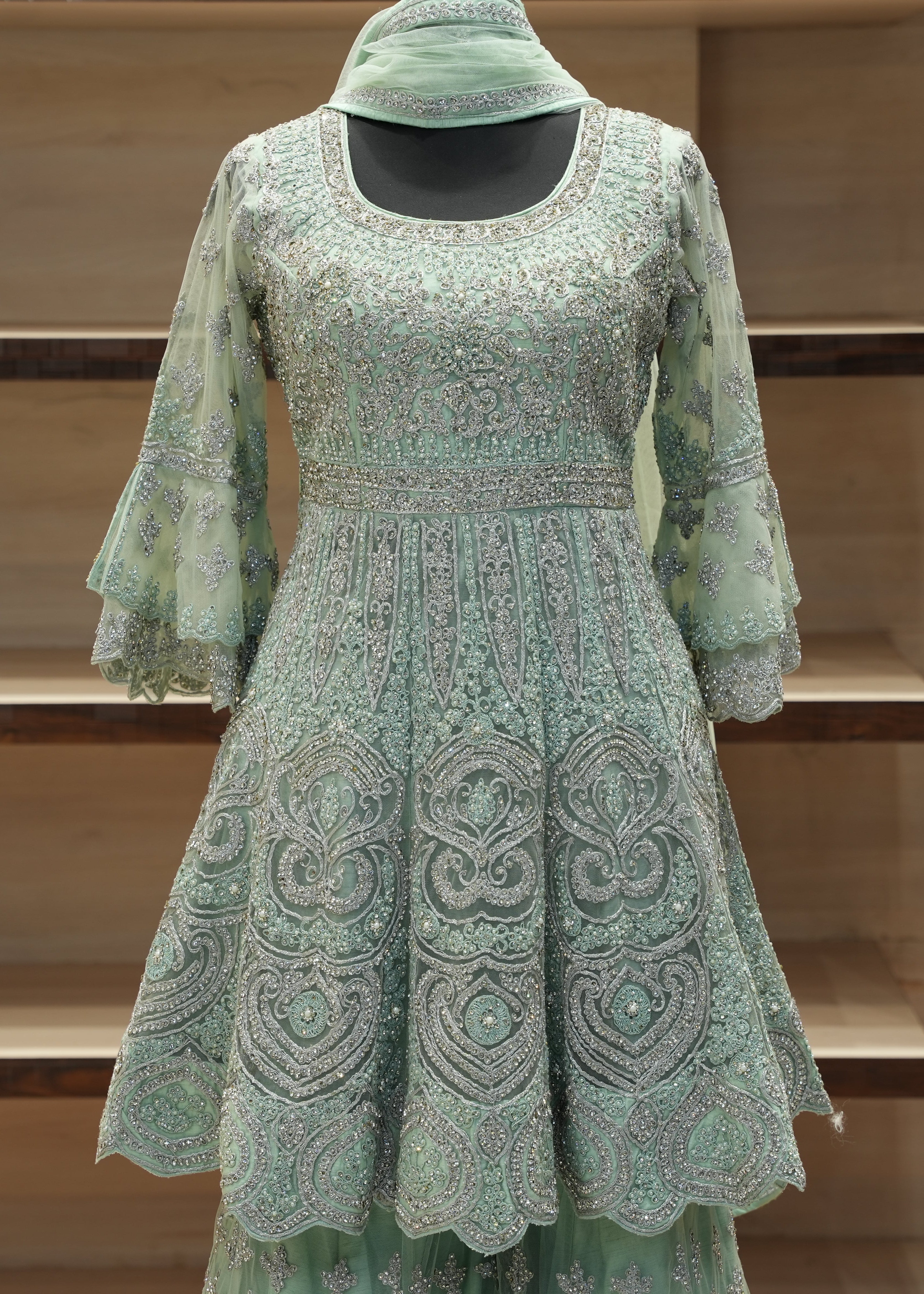 Green embroidered dress with matching headscarf on a wooden shelf background