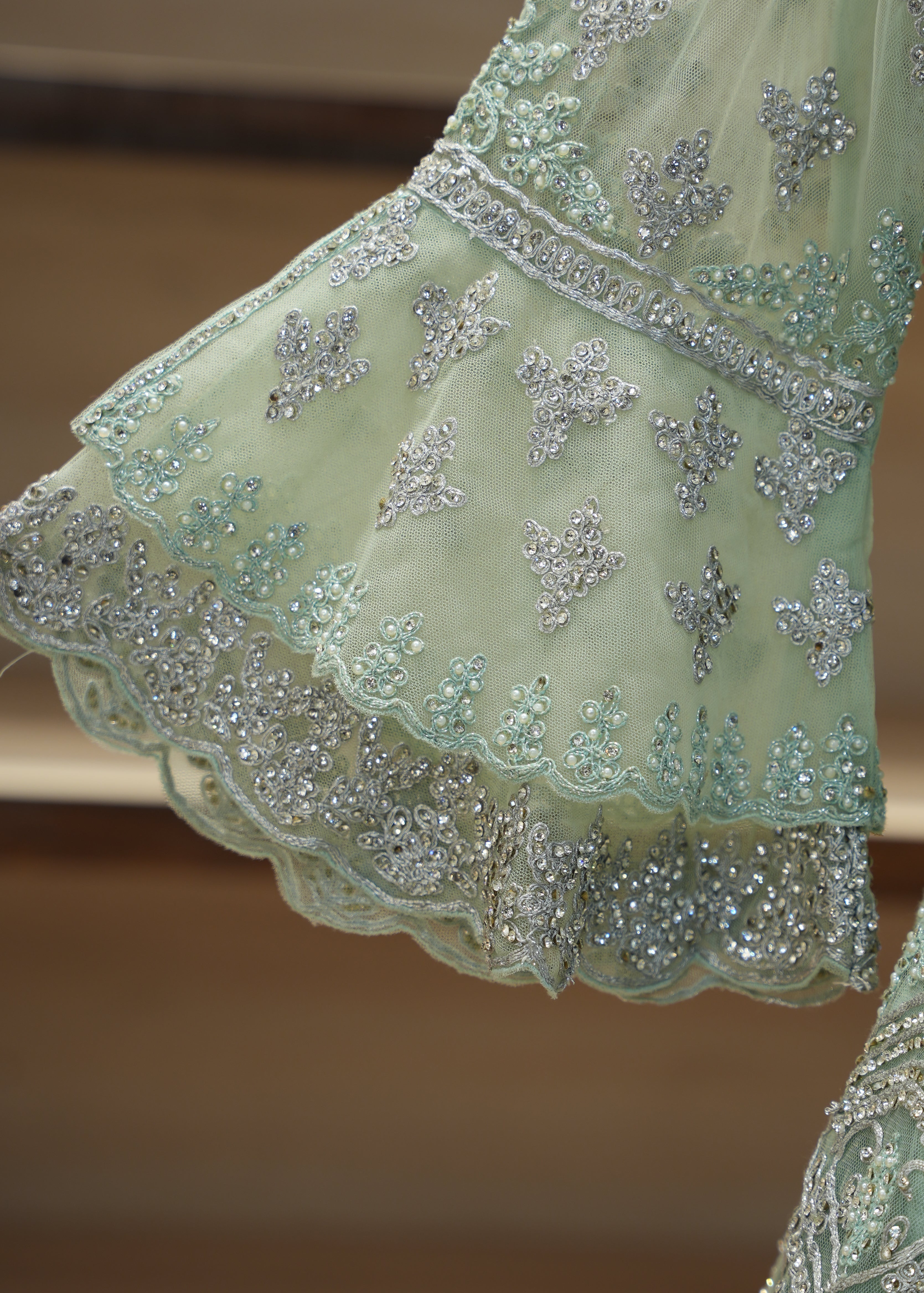 Close-up of a light green embroidered fabric with silver detailing