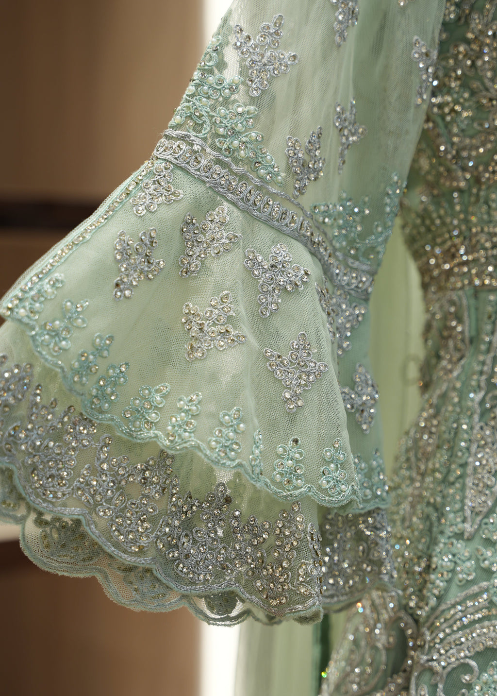 Close-up of a light green embroidered fabric with intricate patterns
