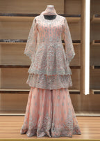 Pink embroidered outfit on a mannequin against a wooden shelf background