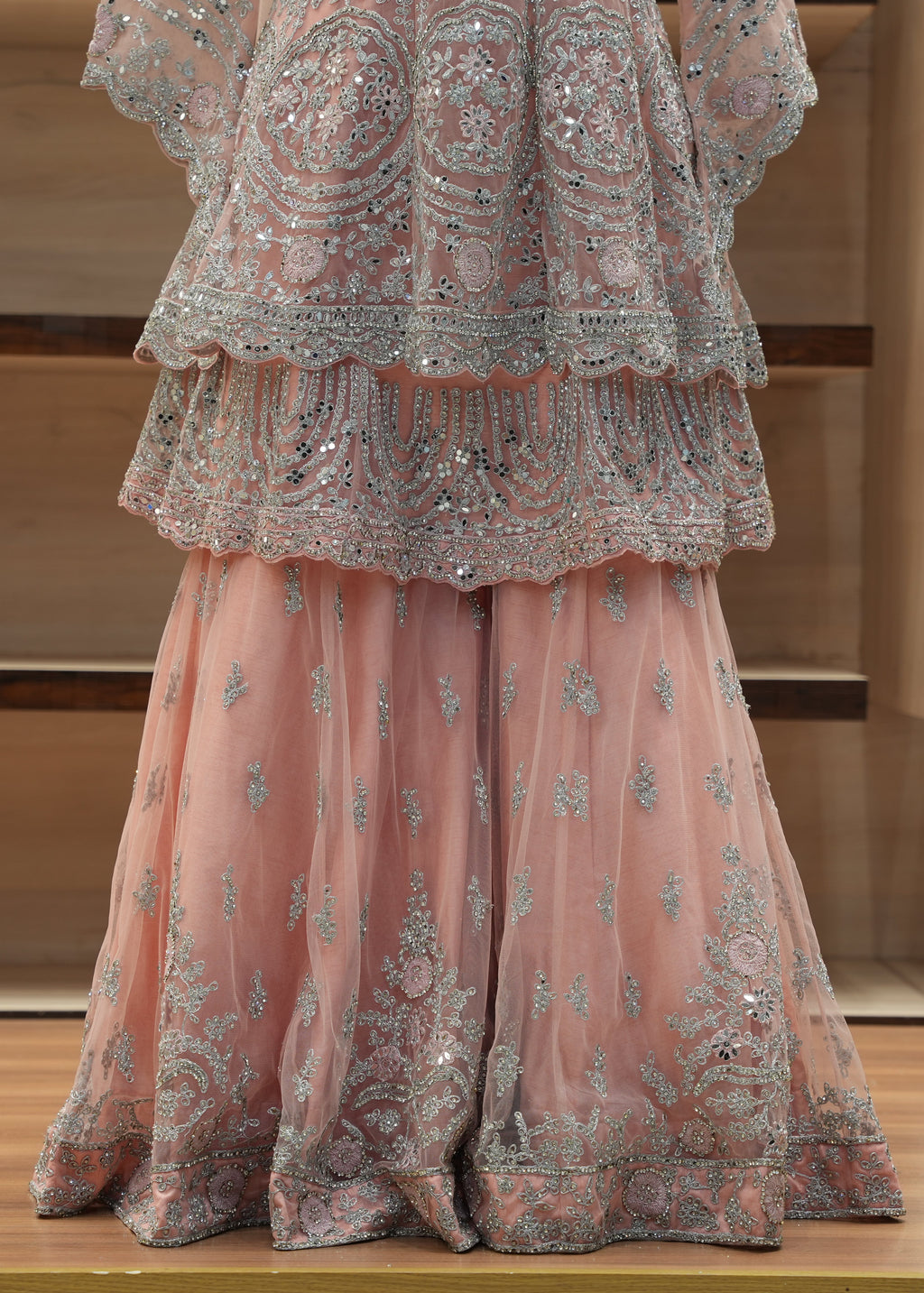 Pink embroidered traditional outfit on a wooden surface