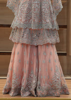 Pink embroidered traditional outfit on a wooden surface