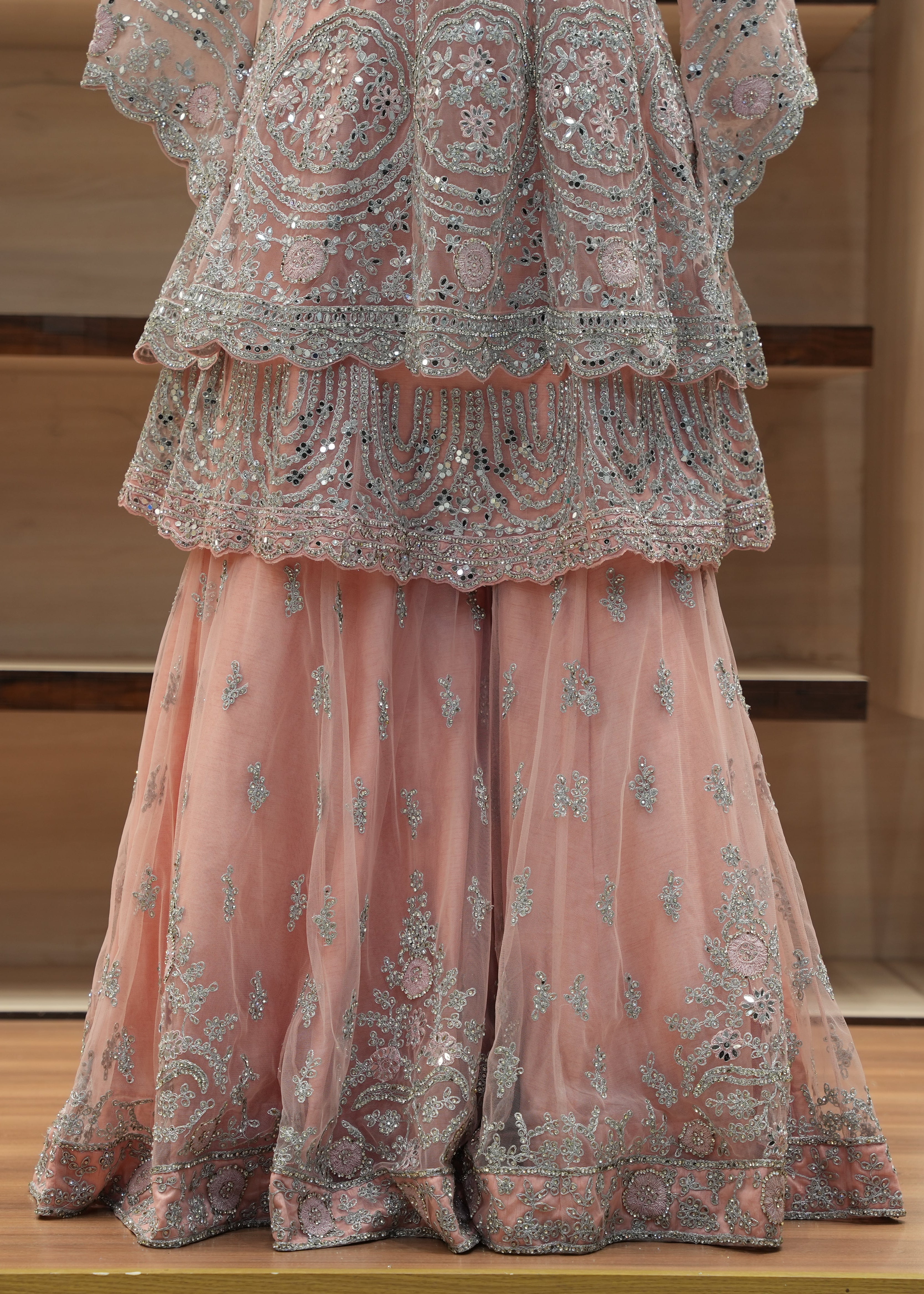 Pink embroidered traditional outfit on a wooden surface