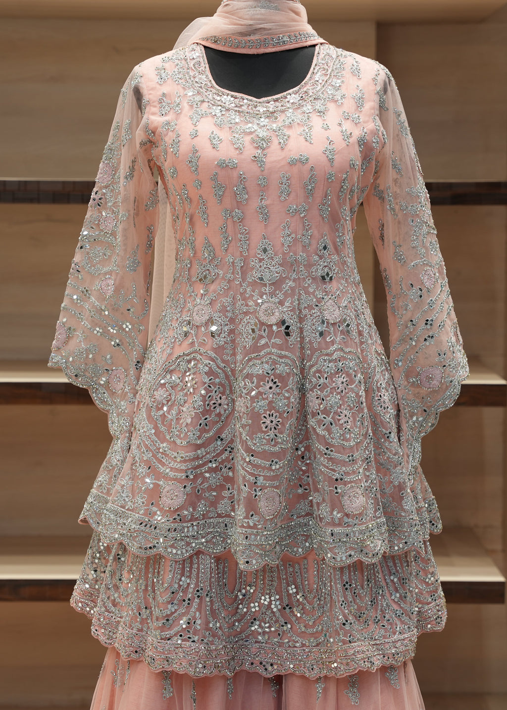 Pink embroidered traditional outfit on a mannequin against a wooden background