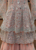Pink embroidered dress with intricate patterns on a wooden background