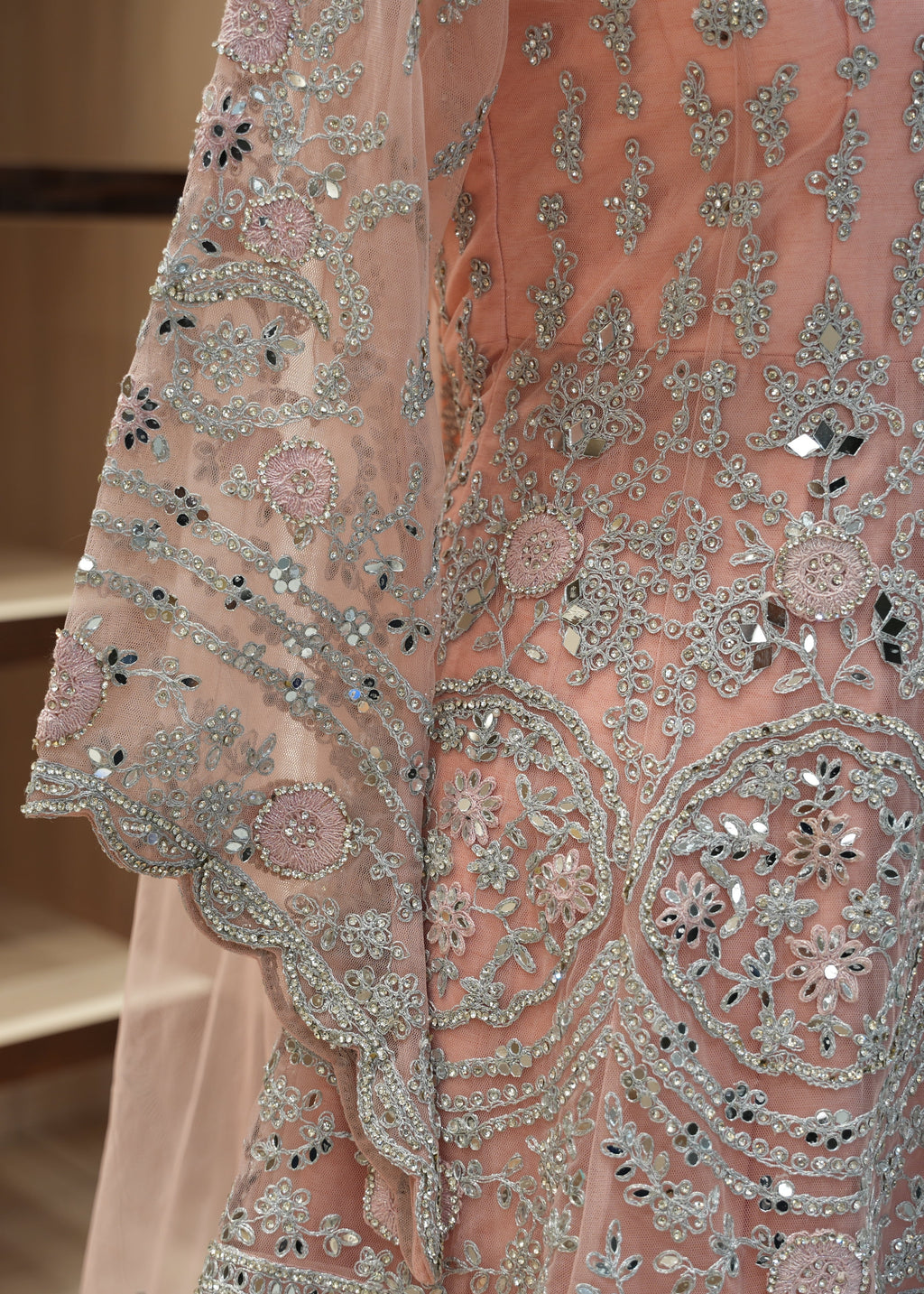 Close-up of a pink embroidered fabric with intricate patterns and embellishments.